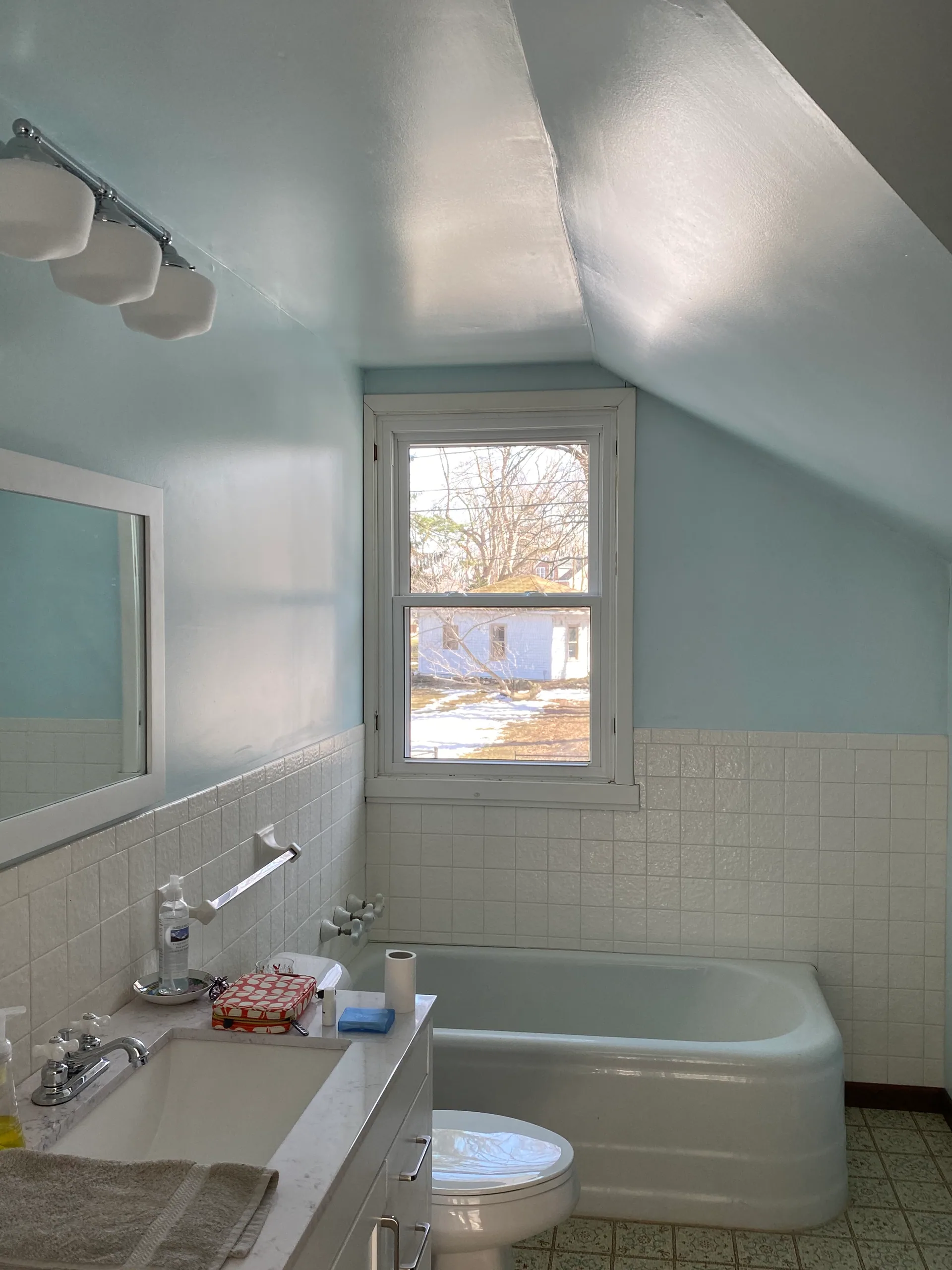 attic bathroom sloped ceiling light blue walls corner tub white tile silver spri