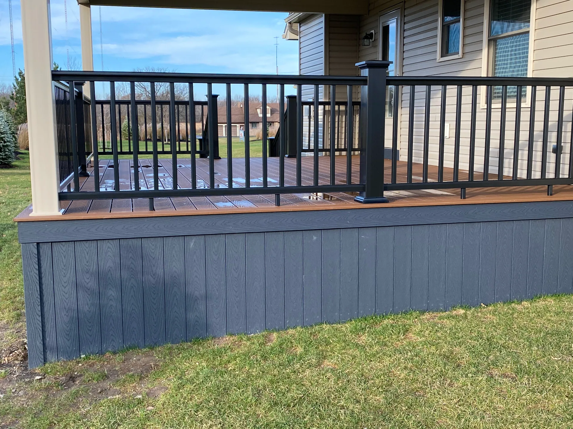 close up composite deck slate gray skirting black railing wet boards silver spri