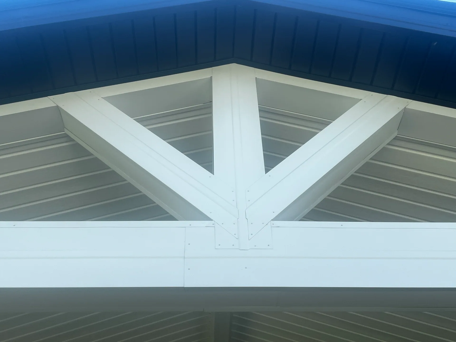 close up white wrapped king post truss navy soffit gable patio cover silver spri