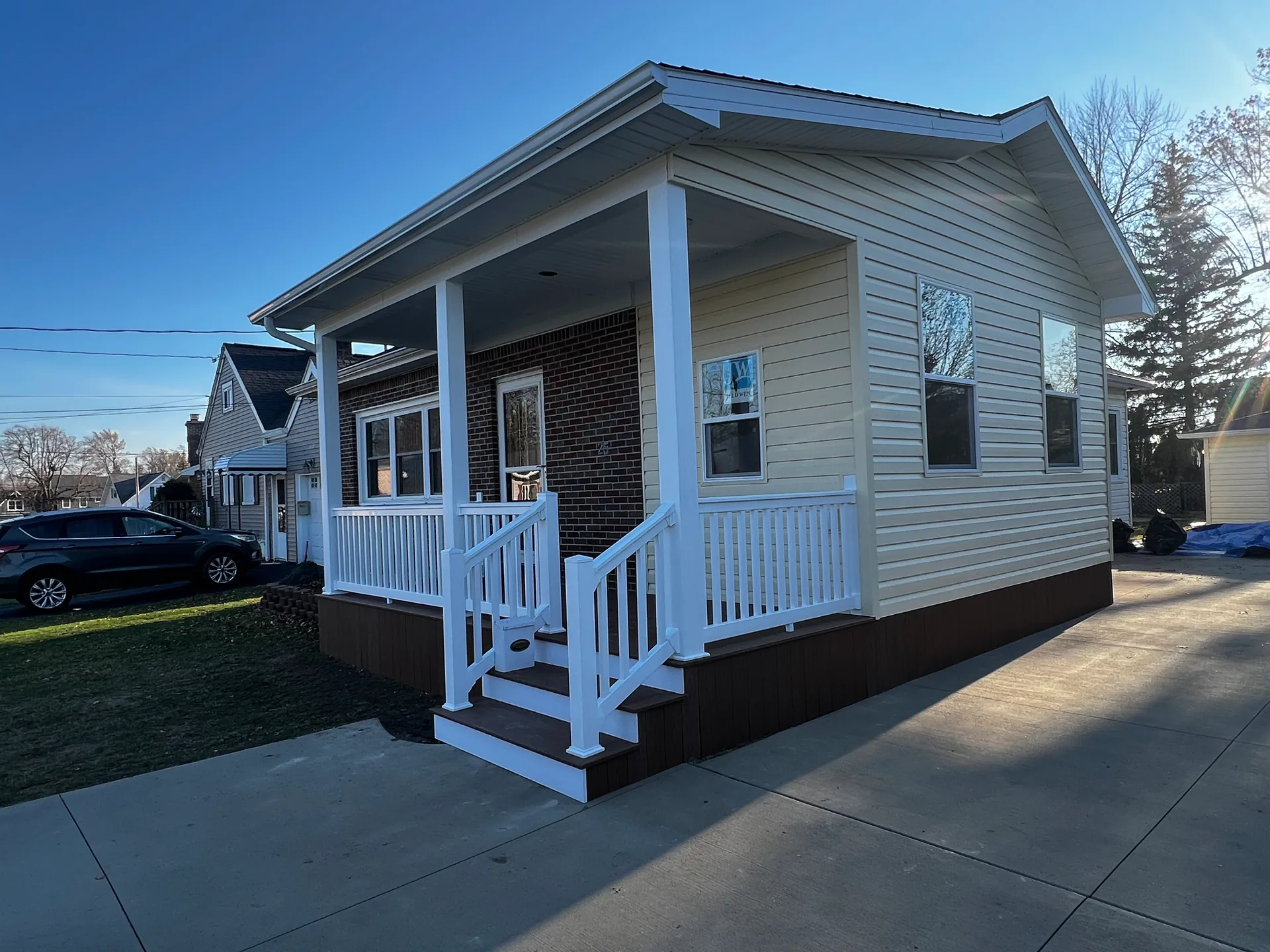 covered front porch brown composite steps brick wall concrete driveway silver sp