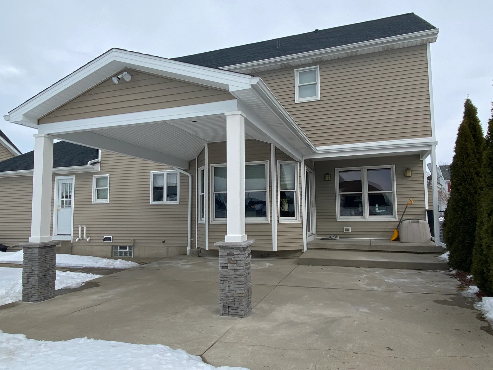 gable patio cover stone base columns tan siding concrete patio silver springs