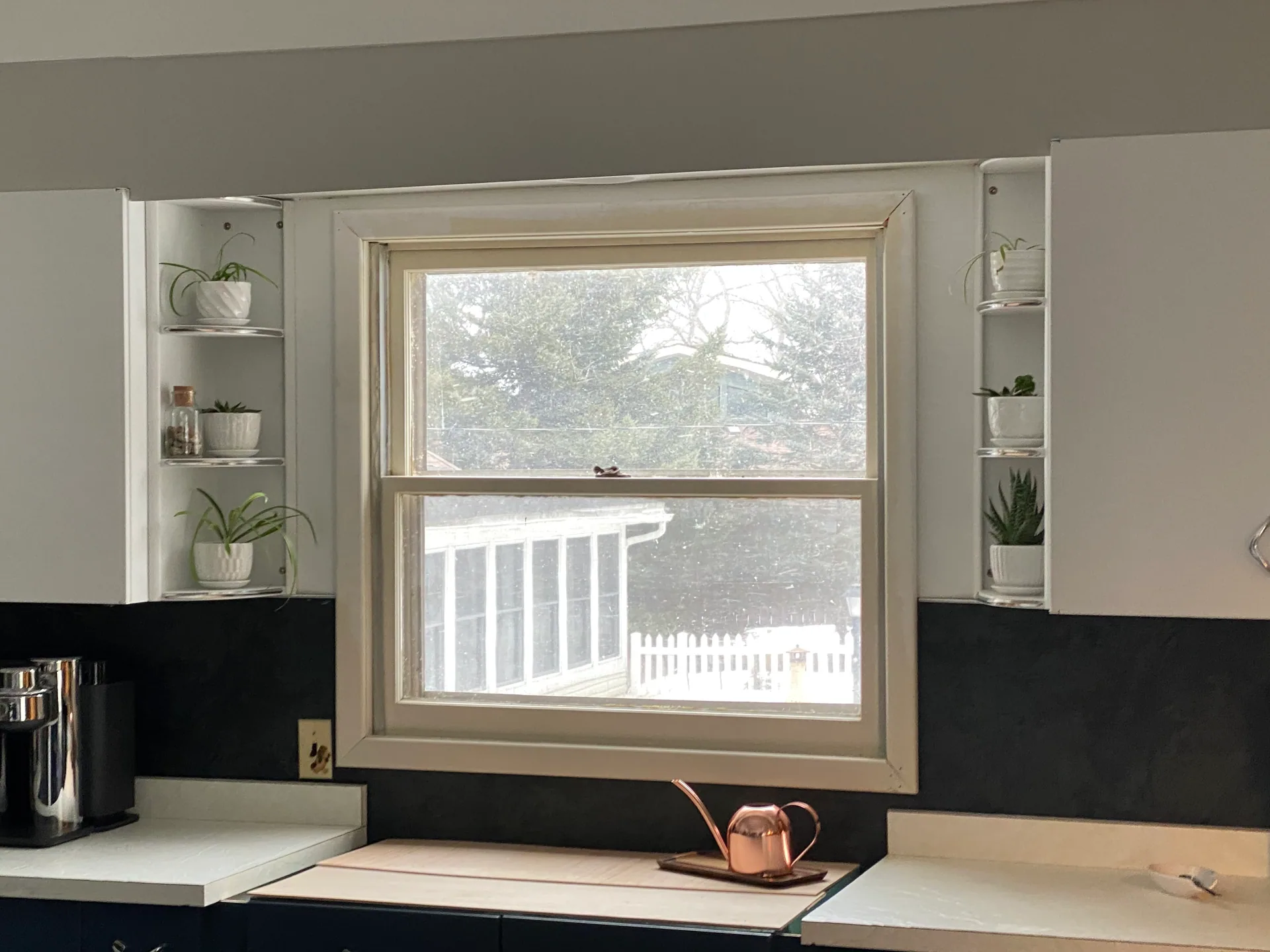 kitchen window old double hung beige frame corner shelves plants backyard view s