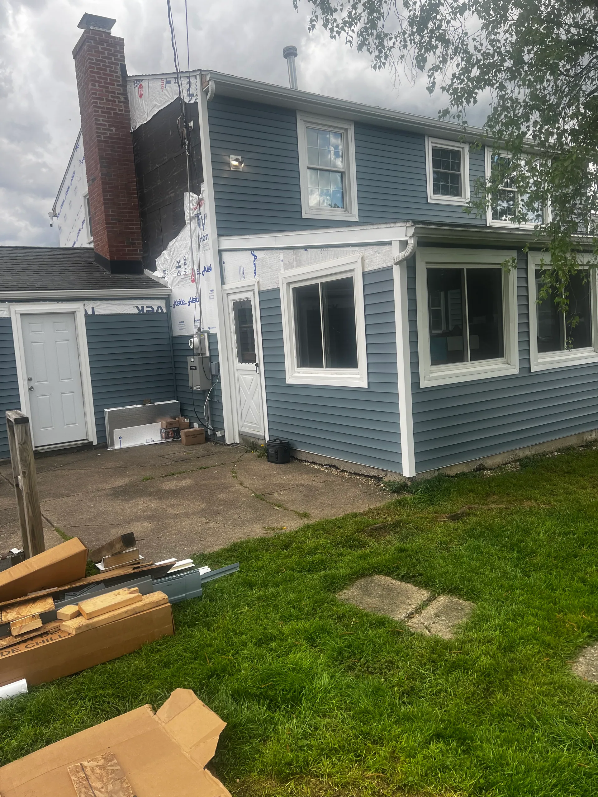 rear elevation partial blue vinyl siding install brick chimney tyvek silver spri